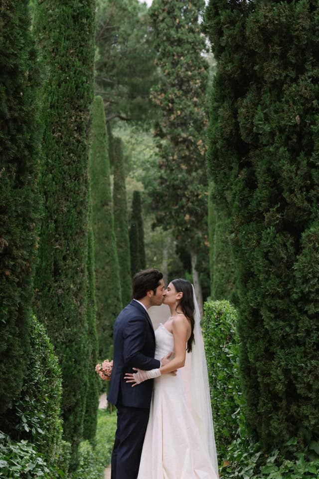 Pareja de novios besándose en un paseo entre cipreses altos